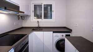 A compact kitchen with a built-in washer and dryer, a window, and a stainless steel sink. - Bright apartment sea view - 4 guests (Torredembarra)