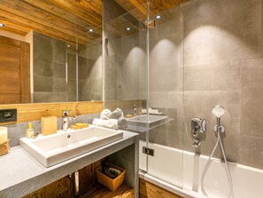 A modern bathroom with a glass shower enclosure, a wooden ceiling, and a large mirror.