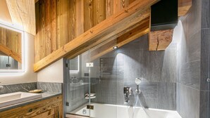 Un bagno moderno con un mobile lavabo in legno, una doccia vetrata e una grande vasca da bagno.