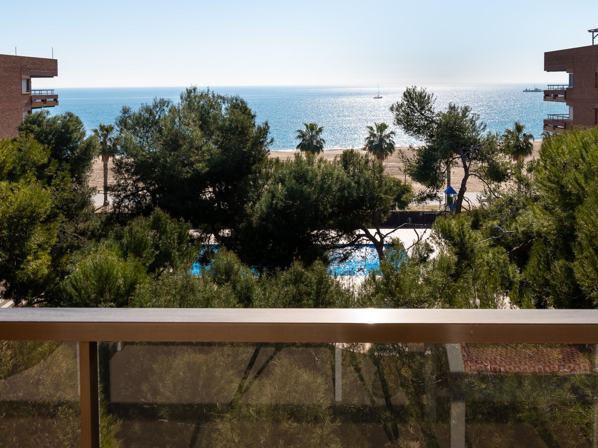 A view of a beach with a pool, surrounded by trees and buildings.