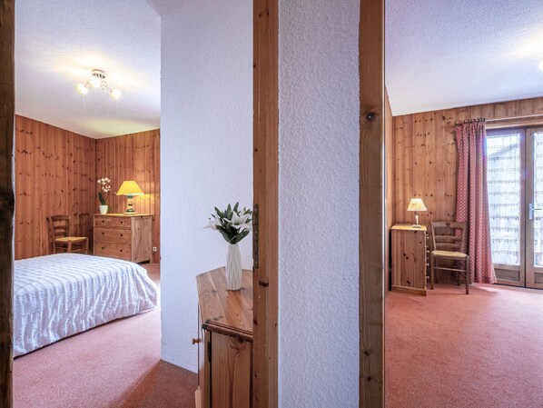 Una habitación con cama, un escritorio con lámpara, una silla y una ventana con cortinas.