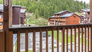 A wooden balcony overlooking a mountainous area with several wooden buildings.