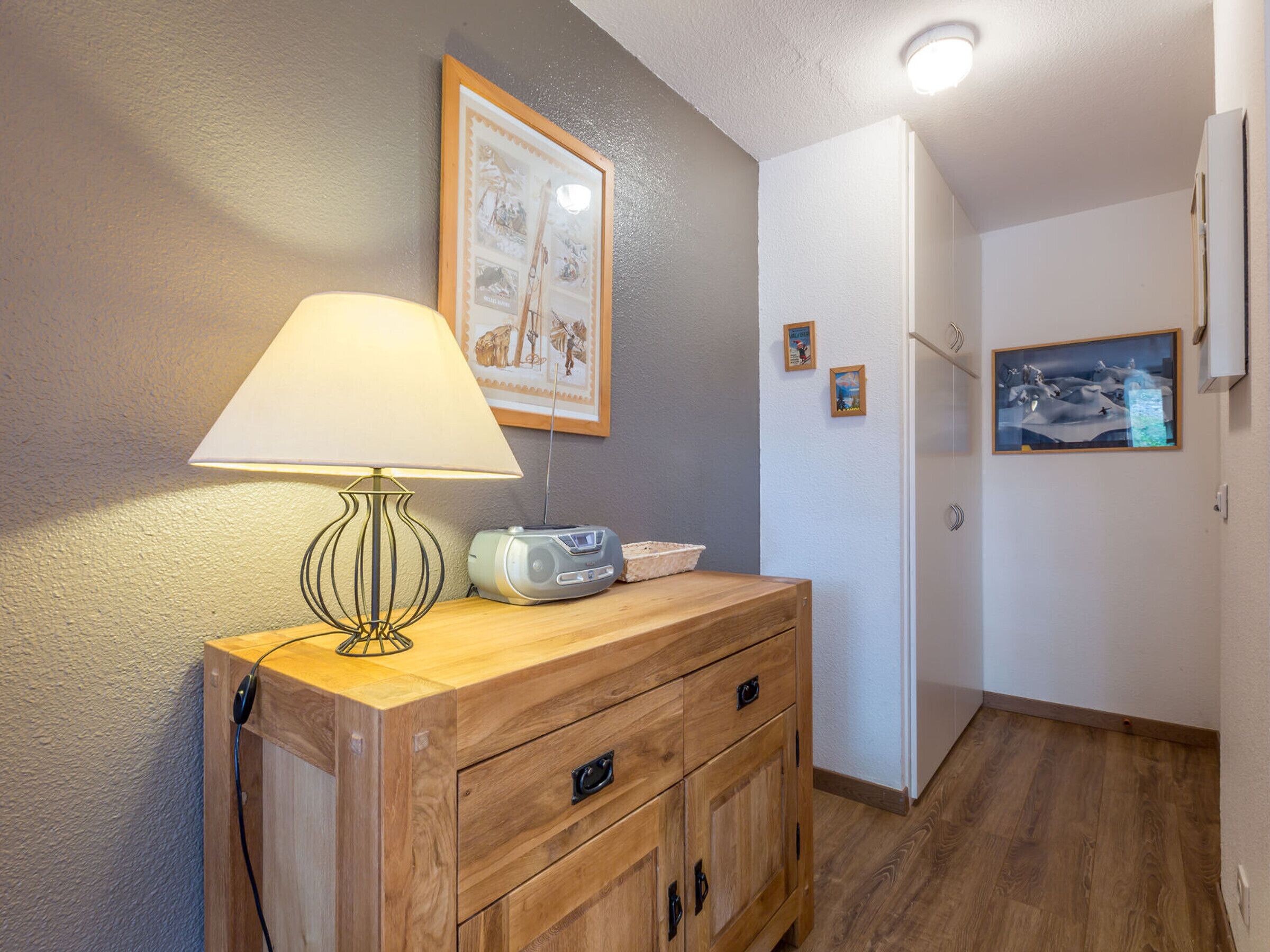 A wooden cabinet with a lamp and radio, a framed picture on the wall, and a white door.