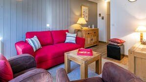 A living room with a red sofa, a wooden cabinet, a small table, and a lamp.