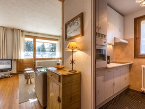 A cozy kitchen with wooden cabinets, a stove, and a window with a view of trees. - Ski-in/ski-out apartment with south terrace and parking in Val-d'Isère (Val-d'Isère)