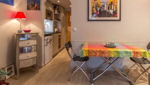 A dining area with a table set for two, a red lamp, and a colorful tablecloth.