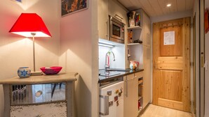 A kitchen with a wooden door, a red lamp, and a bowl on a table.