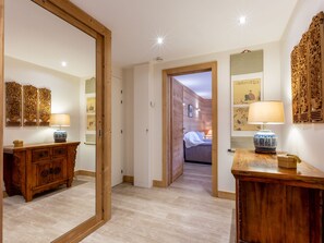 A hotel room with a wooden floor, a bed, a wooden dresser, and a mirror. - Spacious 3-Room Apartment with Balcony, Parking, and WiFi in Val-d'Isère (Val-d'Isère)