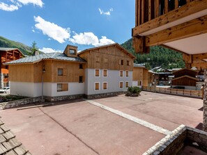 A traditional chalet-style building with a stone foundation, wooden exterior, and multiple windows. - Spacious 3-Room Apartment with Balcony, Parking, and WiFi in Val-d'Isère (Val-d'Isère)