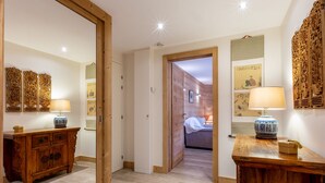 A hallway with wooden flooring, a wooden cabinet with drawers, and a bed in the adjacent room. - Spacious 3-Room Apartment with Balcony, Parking, and WiFi in Val-d'Isère (Val-d'Isère)