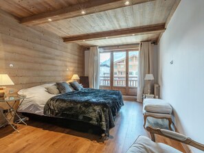 A wooden-paneled bedroom with a bed, bedside tables, and a view through a glass door.
