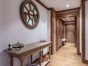 A hallway with a wooden table, a large mirror, and a door leading to another room.