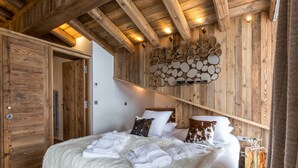 Un dormitorio con techo de madera, una cama con ropa de cama blanca y un arreglo de espejos montado en la pared.
