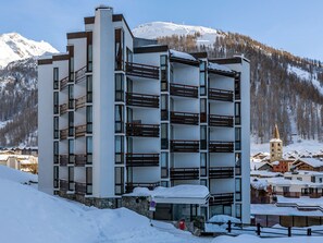 Un hôtel à plusieurs étages, doté de balcons, qui se dresse sur fond de montagnes enneigées.