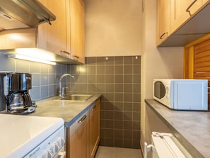 A compact kitchen with a coffee maker, a microwave, and a stove.