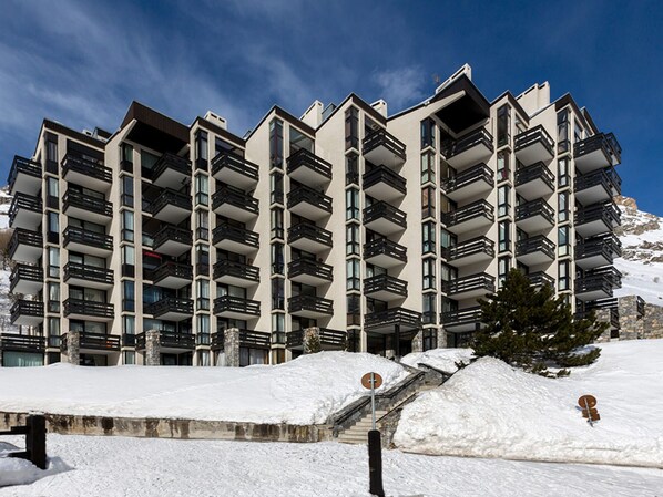 A multi-story hotel with balconies, a snow-covered landscape, and a clear sky.