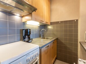 A compact kitchen with a white stove, a coffee maker, and wooden cabinets.
