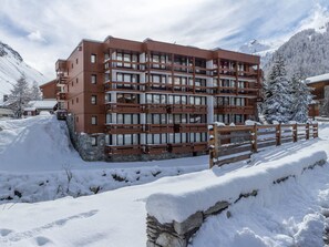 A multi-story hotel with a wooden facade, balconies, and a stone base.