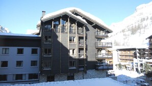A multi-story hotel with balconies, a stone facade, and a mountainous backdrop. - Cozy Studio with Wifi in Central Location, Close to Slopes, Pets Welcome (Val-d'Isère)