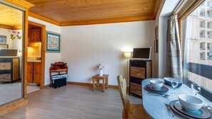 A dining area with a table set for two, a wooden ceiling, and a view of the outside through a window. - Cozy Studio with Wifi in Central Location, Close to Slopes, Pets Welcome (Val-d'Isère)