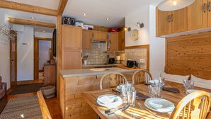 Une cuisine moderne avec des meubles en bois, une table à manger pour quatre personnes et une grande horloge au mur.