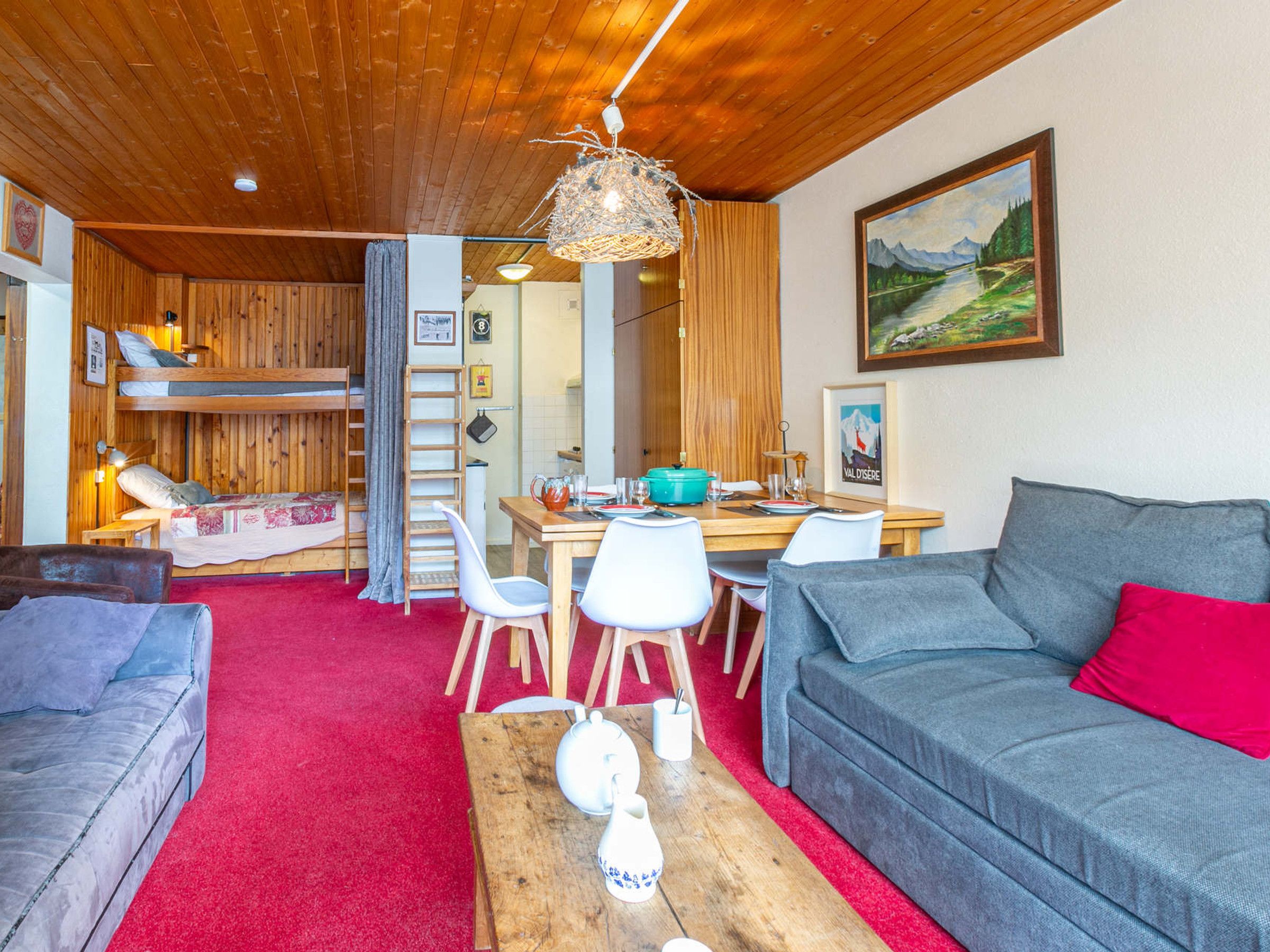 Um quarto acolhedor com uma cama beliche, uma mesa de jantar com cadeiras, um sofá e uma mesa de centro.