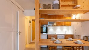 Eine kleine Küche mit Holzausstattung, einem eingebauten Backofen und einer Essecke mit Sitzhocker.