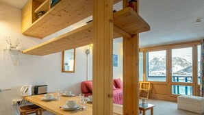 Ein Holzespeisesaal mit Stühlen, einer Couch und Blick auf eine verschneite Landschaft durch große Fenster.