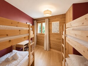 Een kamer met stapelbedden, een bureau en een raam met gordijnen.