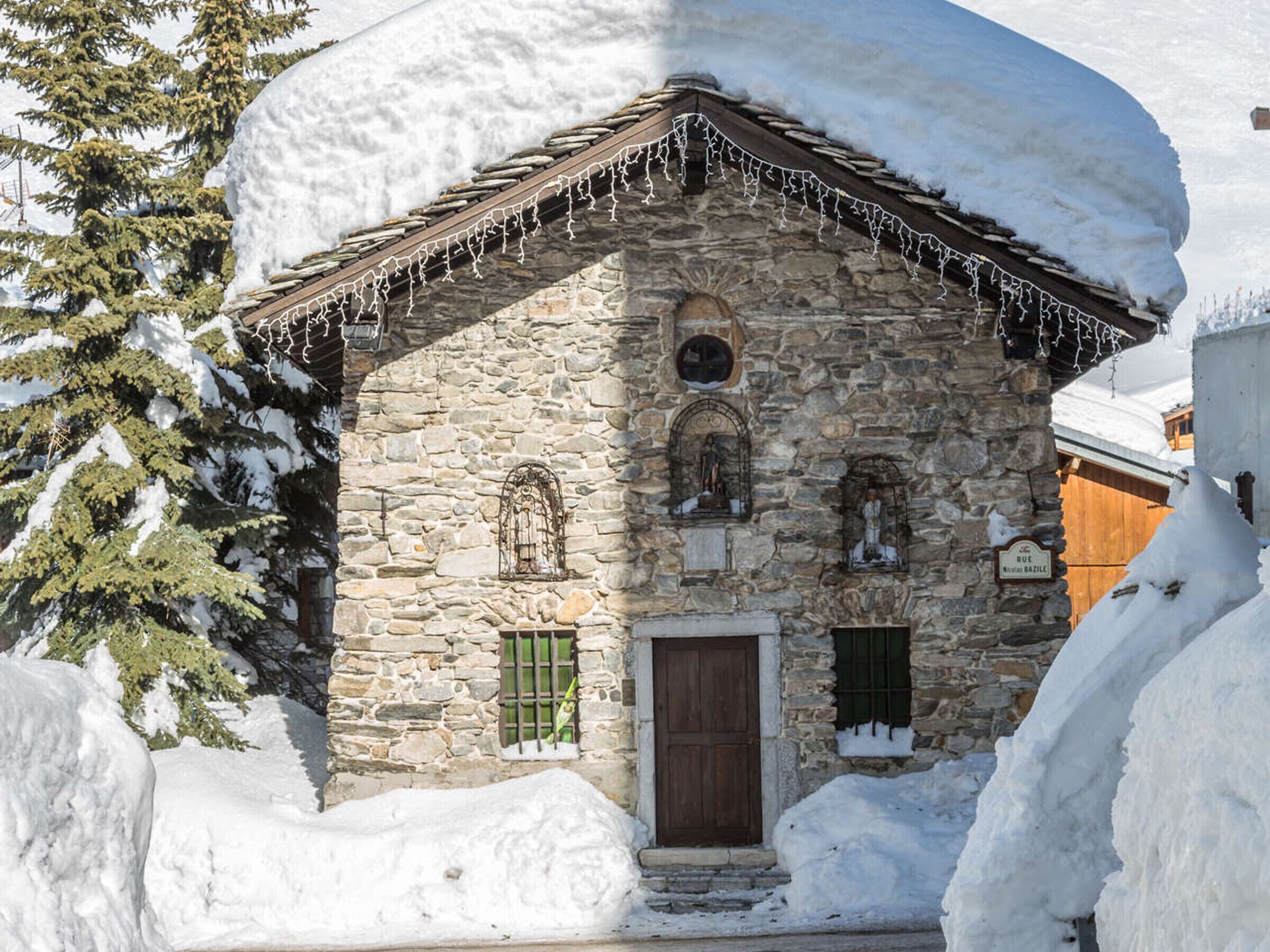 Ein Steinhaus mit einer Holztür und Fenstern, umgeben von Schnee.