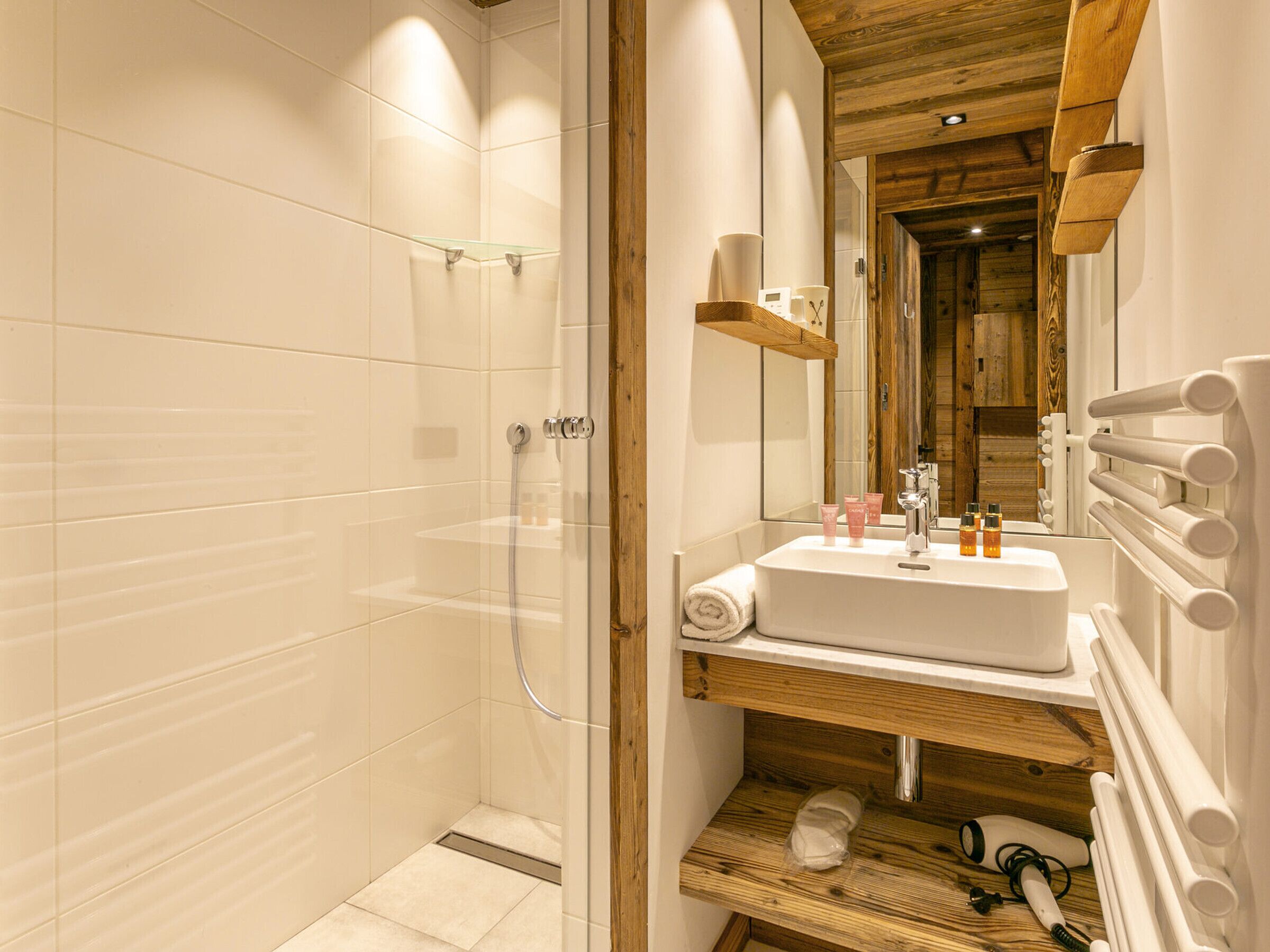 A modern bathroom with a glass-enclosed shower, a wooden vanity with a sink, and a mirror above the mirror cabinet.