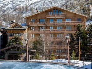 A multi-story wooden building with balconies, surrounded by snow and trees, likely a hotel or resort. - Charming 2-room apartment with WIFI in the heart of Val-d'Isère (Val-d'Isère)