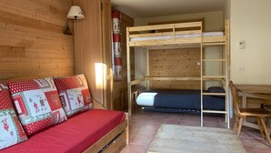A cozy room with a wooden bunk bed, a small wooden table, and a sofa with a red and white patterned blanket. - 28m² Mountain studio for 4 with balcony in Pra-Loup (Pra-Loup)