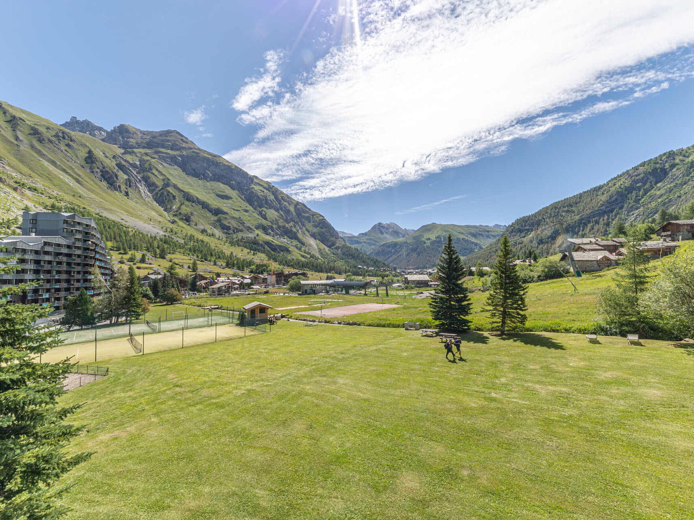 A mountainous landscape with a hotel, a tennis court, and a picnic area.