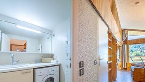 A modern bathroom with a washing machine, a sink, and a mirror.
