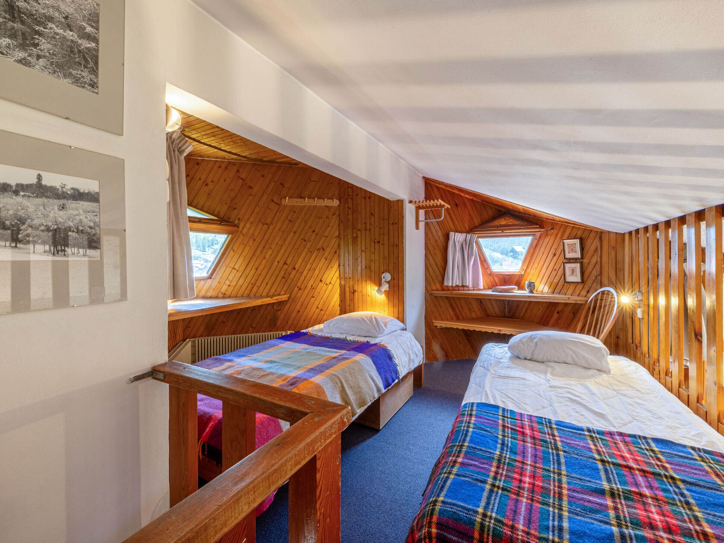 Ein gemütliches Schlafzimmer einer Blockhütte mit zwei Betten, einem kleinen Schreibtisch und einem Fenster.
