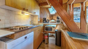 A compact kitchen with wooden cabinets, a Bosch dishwasher, a sink, a microwave, and a coffee maker.