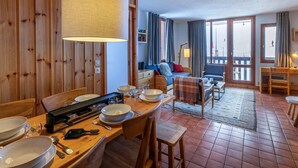 Un comedor acogedor, amoblado con madera, con una mesa grande dispuesta para una comida, un sofá al fondo y vistas al exterior a través de un ventanal.
