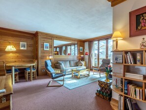 A cozy cabin interior with wooden walls, a sofa, a dining table, and a bookshelf. - Bright studio with WiFi near the slopes (Val-d'Isère)