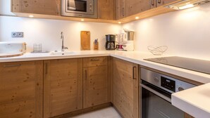 A modern kitchen with wooden cabinets, a built-in microwave, a coffee maker, and a toaster. - Exquisite and Cozy Apartment with WiFi and Garage in Val-d'Isère (Val-d'Isère)