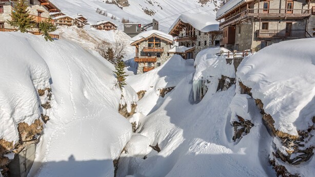 A snow-covered mountain with a wooden chalet and a stone building with balconies. - Exquisite and Cozy Apartment with WiFi and Garage in Val-d'Isère (Val-d'Isère)