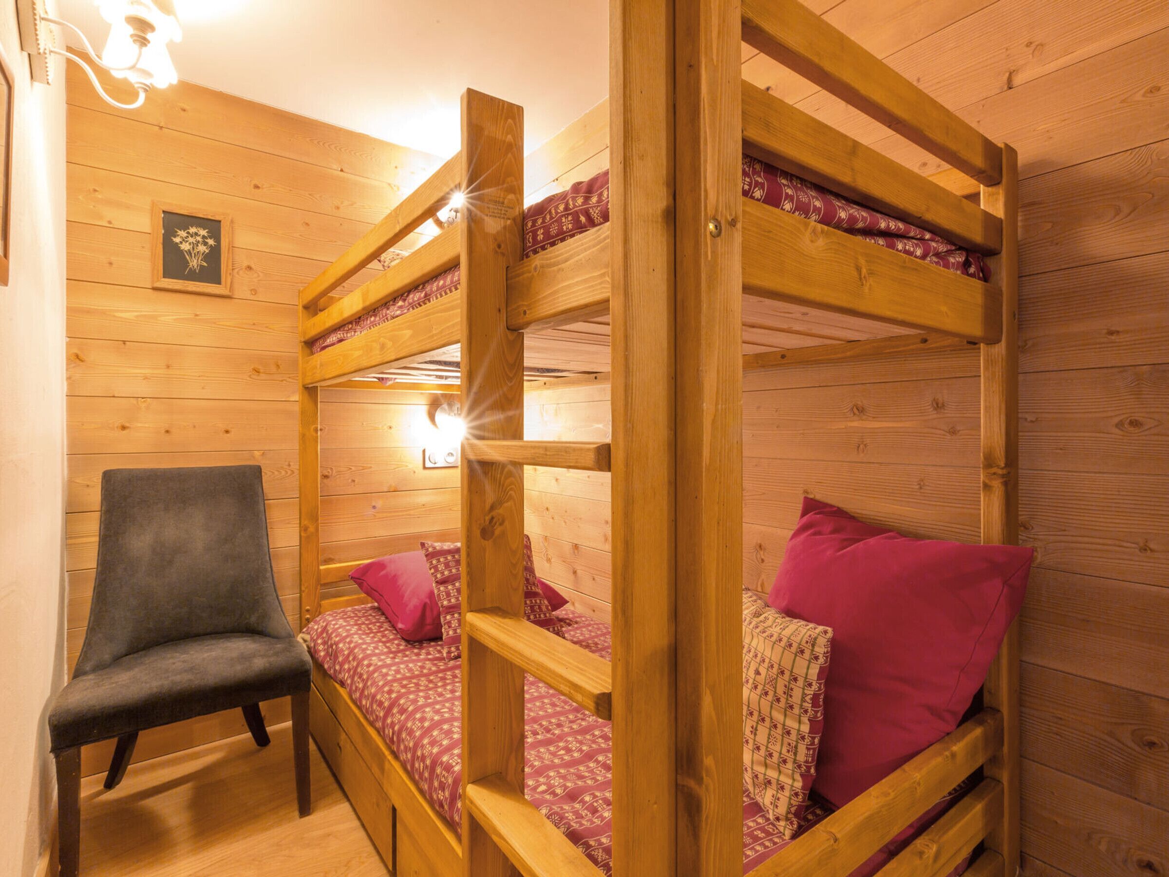 Une chambre avec des lits superposés, des murs en bois, une chaise et un tableau encadré accroché au mur.