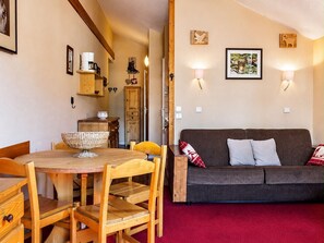 A cozy living room with a wooden dining table, chairs, a sofa, and a red carpet. - Cozy studio cabin with wifi and parking in Val-d'Isère (Val-d'Isère)