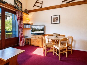 A cozy room with a television, wooden furniture, a red carpet, and a window with curtains. - Cozy studio cabin with wifi and parking in Val-d'Isère (Val-d'Isère)