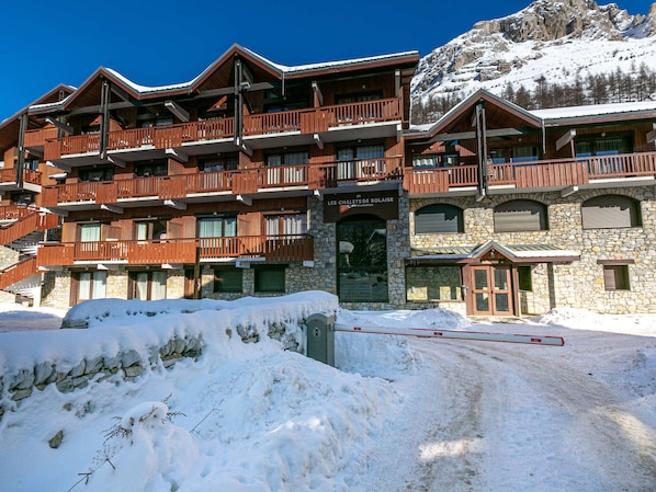 A multi-story wooden building with balconies, a stone facade, and a sign reading "Chalet de Soleil".