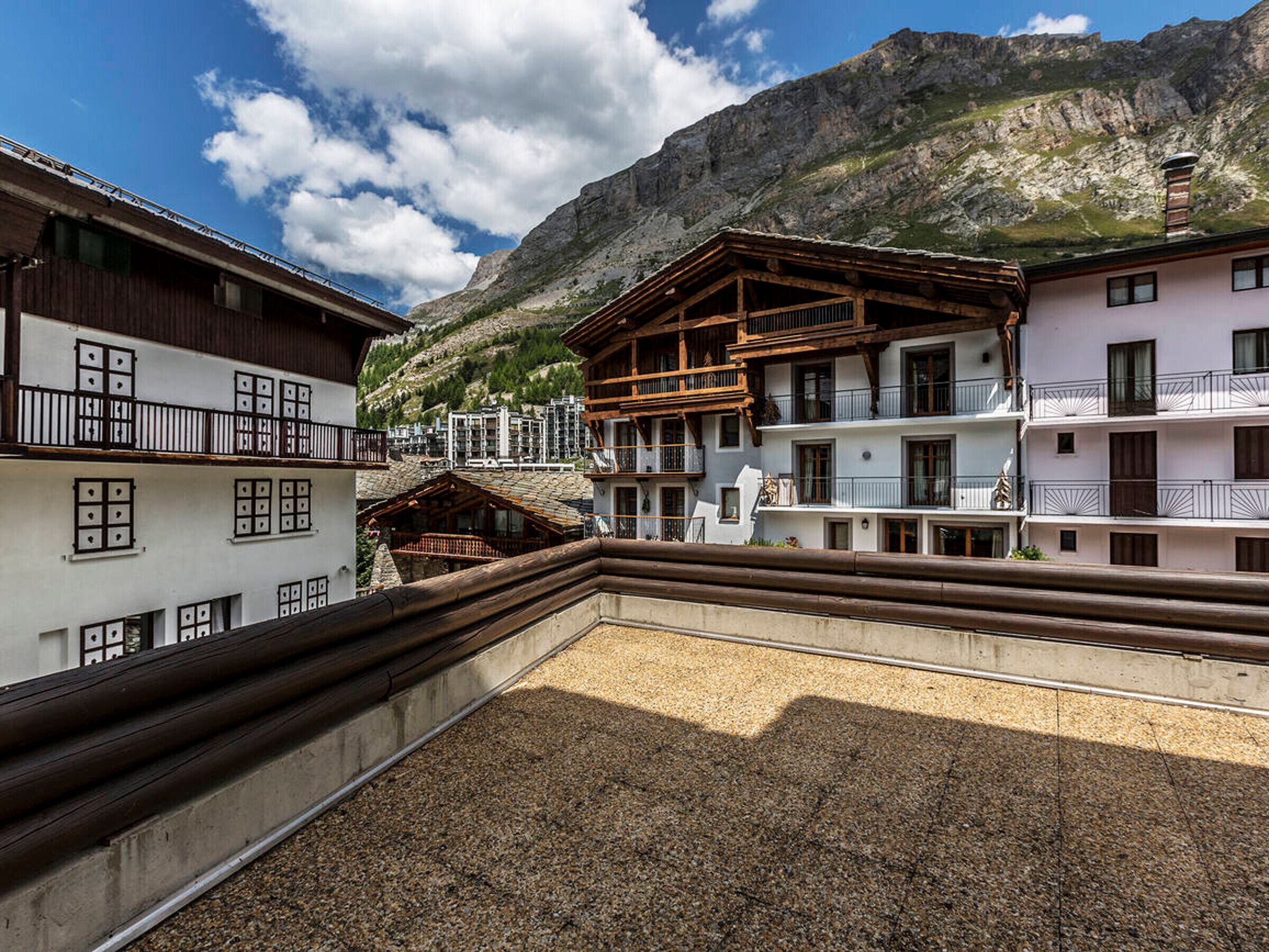 A traditional alpine building with wooden balconies and a mountain backdrop.
