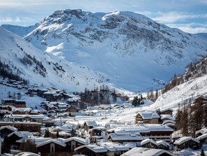 Een bergstad bedekt met sneeuw, met traditionele houten gebouwen, een skilift en een helder uitzicht op de berg.