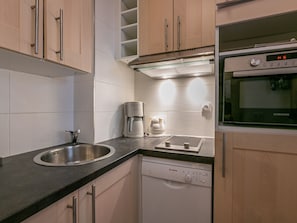 A modern kitchen with a stainless steel sink, a coffee maker, a Bosch dishwasher, and a Samsung oven.