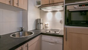 Una cocina moderna con un lavamanos de acero inoxidable, una cafetera, un lavavajillas Bosch y un horno Samsung.