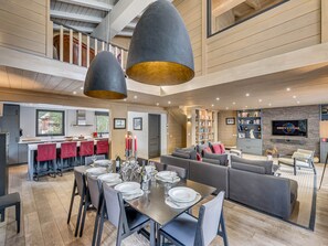 A spacious living area with a dining table set for six, a sofa, and a television.